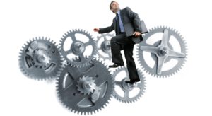 A businessman cycling a gear that is in turn moving other gears