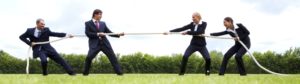 Four business people playing tug of war with a rope