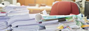 a desk completely covered with piles of paper