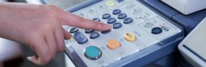 a hand pushing a button on a printer keypad