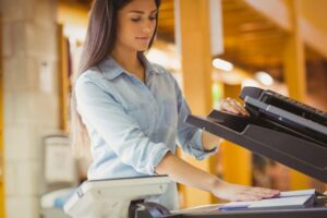 Business woman standing in front of an office copier signifying copier rentals