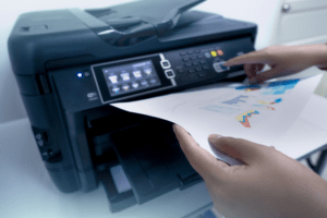 Close-up of a person using a laser printer to print colorful charts and graphs, highlighting the efficiency and quality of laser printer output.
