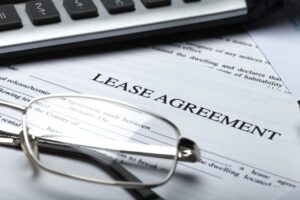 A lease agreement document titled 'Lease Agreement' placed under a pair of eyeglasses and a calculator, representing an office equipment lease arrangement.